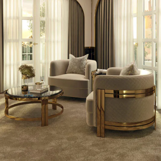 Contemporary Round Smoked Glass Coffee Table A luxurious living room boasts two beige, quilted armchairs with gold accents, a Contemporary Round Smoked Glass Coffee Table, and a beautiful vase of flowers. The space is illuminated by natural light streaming through floor-to-ceiling windows adorned with white curtains and grey drapes.