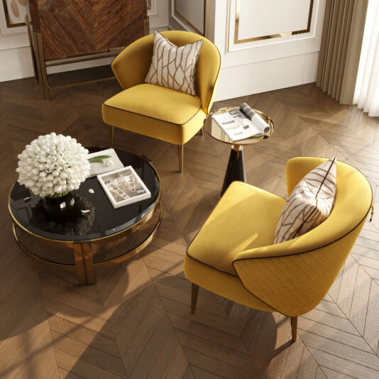 A cozy seating area features two Contemporary Winged Occasional Armchairs in vibrant yellow, each adorned with patterned pillows. These chairs are arranged around a round glass coffee table that holds a bouquet of white flowers, books, and magazines. The space boasts wood herringbone floors, elegant paneling, and a side table with a book.
