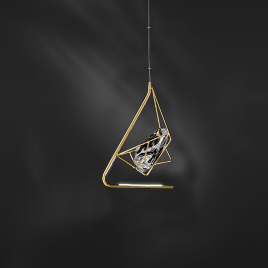 A modern Crystal Rock Pendant Light hangs against a dark background. The light fixture features a gold frame with geometric shapes and a cylindrical glass element containing the bulb, embodying a minimalist and artistic design that casts a subtle glow.