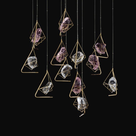 A cluster of Crystal Rock Pendant Lights showcases angular, geometric gold frames encasing irregularly shaped glass pieces. The lights are suspended at varying heights against a black background, creating a stylish and artistic visual effect.