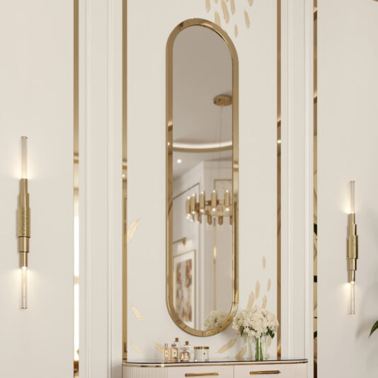 A luxurious interior showcases the Large Lozenge Modern Wall Mirror framed in gold, set against a patterned wall with gold accents. Two sleek wall-mounted light fixtures are positioned on each side of the mirror. Below, a countertop displays a bouquet of white flowers and various decorative bottles, while ceiling lights reflect beautifully in the mirror.