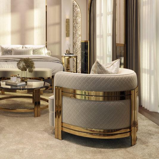 Modern Curved Armchair With Brass Frame A luxurious bedroom featuring the Modern Curved Armchair With Brass Frame, adorned with a quilted design that adds contemporary flair to the space. The room includes a bed with a tufted headboard, matching pillows, a round mirror coffee table, and floor-length curtains. The color scheme is neutral and elegant, with gold highlights.