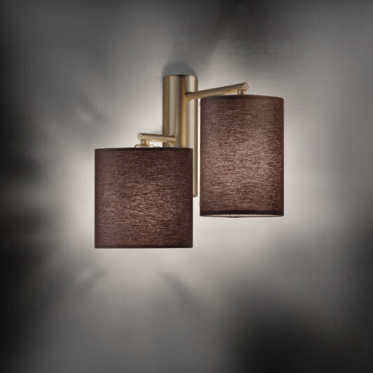 The Modern Double Wall Light With Shades showcases two cylindrical brown lampshades mounted on a sleek metallic gold base, providing a soft, ambient glow against a light grey wall.