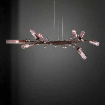 Pink Glass Branch Chandelier With Swarovski Crystal Flowers The Pink Glass Branch Chandelier With Swarovski Crystal Flowers is a contemporary piece designed to mimic the look of a tree branch, featuring multiple cylindrical, pink-tinted light fixtures and adorned with Swarovski crystal flowers. This elegant chandelier hangs from thin wires against a gray gradient background, exuding style and sophistication.