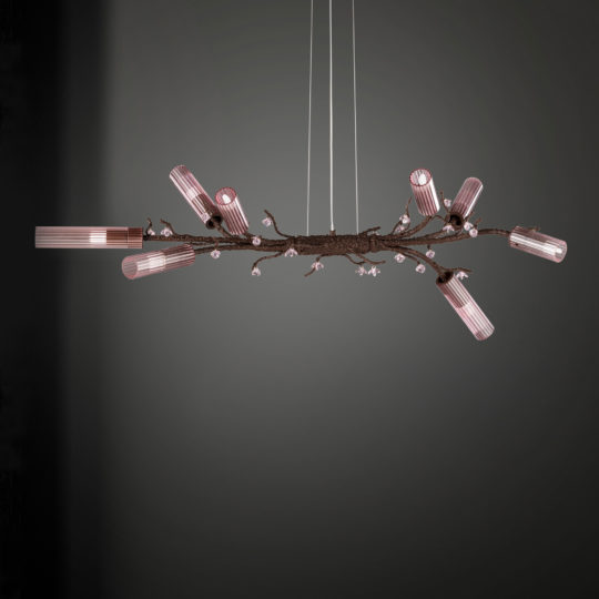 The Pink Glass Branch Chandelier With Swarovski Crystal Flowers is a contemporary piece designed to mimic the look of a tree branch, featuring multiple cylindrical, pink-tinted light fixtures and adorned with Swarovski crystal flowers. This elegant chandelier hangs from thin wires against a gray gradient background, exuding style and sophistication.