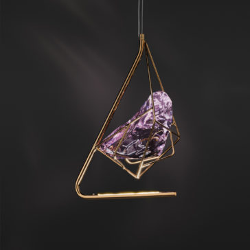 The Rose Crystal Rock Pendant Light features a modern design with a geometric gold frame encasing a large, faceted rose crystal rock. Suspended against a dark background, this pendant light gracefully highlights the intricate details and reflective qualities of the crystal.