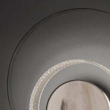 Contemporary Round Wall Light With Marble Effect Close-up of the Contemporary Round Wall Light With Marble Effect, showcasing its concentric circle design. The innermost circle is softly illuminated and resembles marble, while two larger, darker rings enclose it, forming an abstract and minimalist aesthetic. The background features a smooth, dark surface.