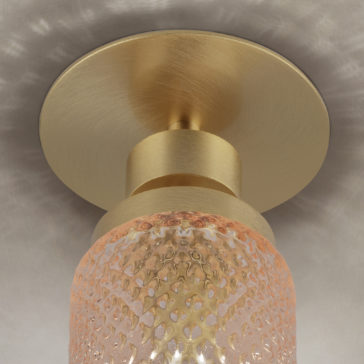 Close-up view of the Spotlight With Balloton Effect Glass Shade, showcasing a textured, cylindrical glass shade paired with a metallic gold base. This modern ceiling light fixture boasts a sophisticated, minimalist design with intricate patterns that cast subtle reflections on the ceiling.