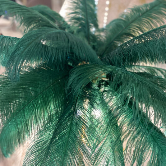 Striking Palm Tree Floor Lamp With Green Feathers Close-up image of a lush green palm frond. The sun shines through the delicate, feathery leaves, reminiscent of the intricate structure and vivid color of the Striking Palm Tree Floor Lamp with Green Feathers. The background is softly blurred, drawing focus to the central fronds.