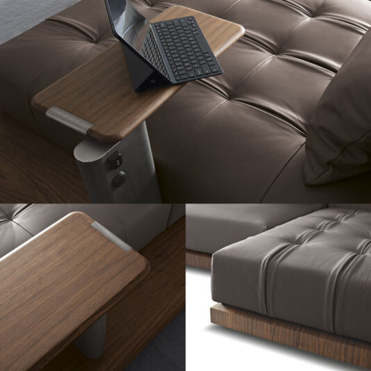 A modular wooden bedside table with a built-in reading lamp and an integrated light switch accompanies a plush, tufted leather bed frame on a wooden platform. An open laptop sits on the table surface, reflecting the craftsmanship seen in the Contemporary High End Modular Corner Sofa.