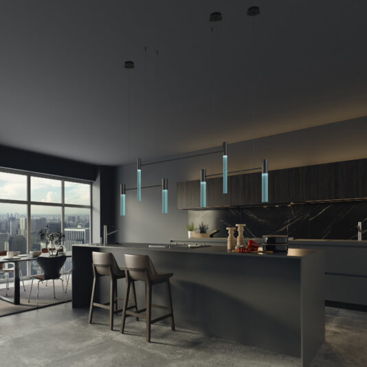 A modern kitchen with sleek grey countertops, black cabinets, and a black marble backsplash. Several Contemporary Modular Glass Tube Chandeliers hang above the island with two bar stools. Large windows offer a view of the cityscape in the background, creating a dimly-lit ambiance.