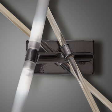Contemporary Murano Glass Tube Wall Light A detailed view of the Contemporary Murano Glass Tube Wall Light reveals its intertwined translucent tubes that emit a gentle white light. The fixture is elegantly mounted on a rectangular black base, set against a gray background, delivering a sleek and minimalist aesthetic.
