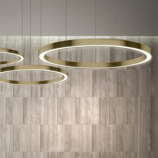 Contemporary Round Downlight Chandeliers with gold trim hang from the ceiling against a backdrop of vertical wooden panels. The light gray ceiling enhances the minimalist and elegant interior design.