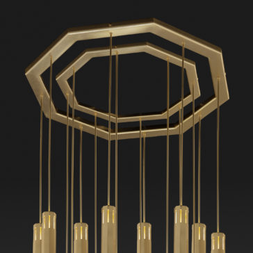 Large Modern Geometric Pendant Style Chandelier The Large Modern Geometric Pendant Style Chandelier, featuring an octagonal brass frame, showcases multiple vertical rod-like lights suspended from it against a black background. The lights are encased in cylindrical glass that softly diffuses the illumination.