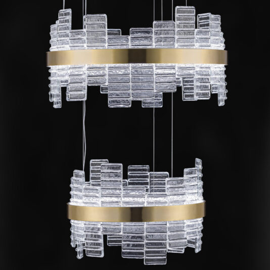 The **Large Modern Tiered Venetian Glass Chandelier** features two circular tiers of textured Venetian glass blocks, each encircled by a horizontal brass band. The illuminated glass blocks create a striking and elegant light fixture against a black background.