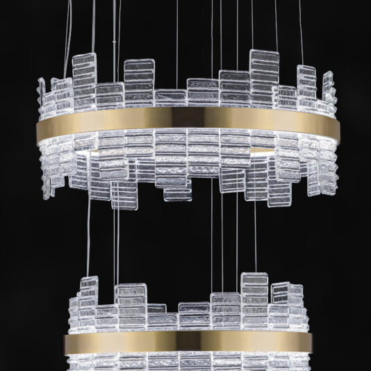 A close-up shot of the Large Modern Tiered Venetian Glass Chandelier showcases its intricate and elegant design, featuring two circular gold bands that support numerous clear rectangular glass pieces arranged in a staggered pattern, all set against a black background.