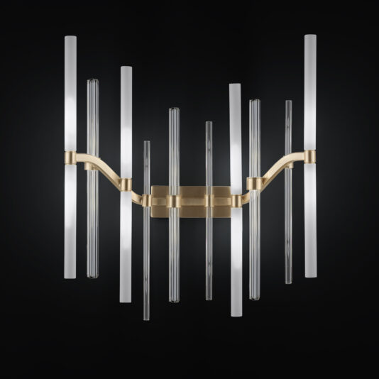 The Large Vertical Murano Glass Tube Wall Light features a gold base with an array of large vertical Murano glass tubes, both clear and frosted, extending outward. The illuminated tubes create a striking and elegant lighting fixture against a dark background.