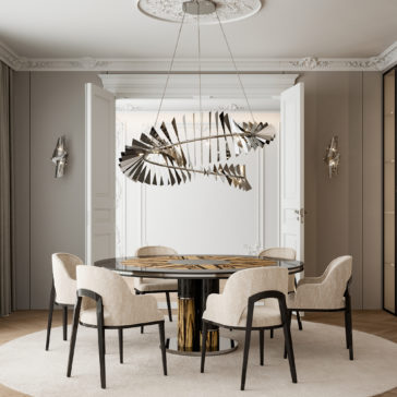 A modern dining room showcases a round wooden table with metallic accents, surrounded by six upholstered Modern Art Deco Style Tub Dining Chairs in beige. Overhead, an abstract, fan-like chandelier is suspended. The room features elegant double doors, ornate molding, and minimalist wall sconces that evoke a modern Art Deco aesthetic.