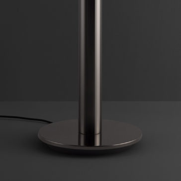 Modern Faceted Crystal Floor Lamp The Modern Faceted Crystal Floor Lamp features a sleek metallic base and a tall, cylindrical stand, showcased against a dark gray background. A black power cord extends from the base's back, while the lighting highlights the smooth and reflective metal surface.