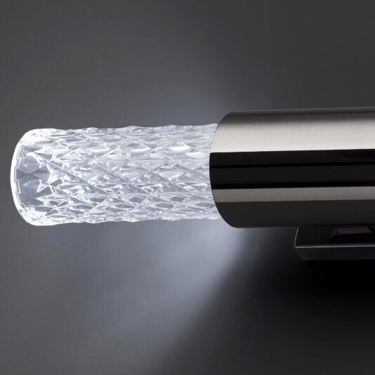 Modern Faceted Crystal Wall Light Introducing the Modern Faceted Crystal Wall Light, featuring a textured cylindrical lantern crafted from clear faceted glass. This elegant fixture emits a soft glow, beautifully highlighting the intricate diamond pattern on the glass. The design is completed with a sleek, metallic casing for a contemporary finish.