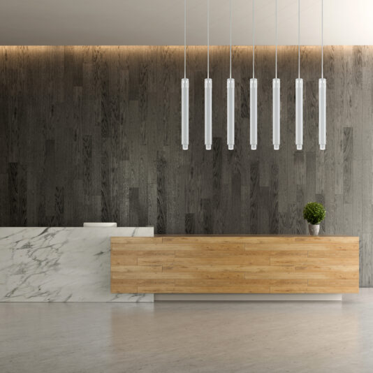 Modern Geometric Pendant Light A modern reception area showcasing a sleek marble desk and a wooden counter. Behind the counter, a dark, textured wall provides a striking backdrop. Several Modern Geometric Pendant Lights hang from the ceiling, and a small plant adds a touch of greenery.