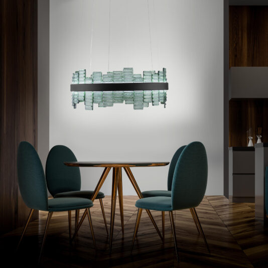 A modern dining area featuring a round table and four teal upholstered chairs. Above the table, a Modern Round Venetian Glass Chandelier made of layered glass pieces hangs from the ceiling. The room boasts dark wooden walls and a chevron-patterned wooden floor.