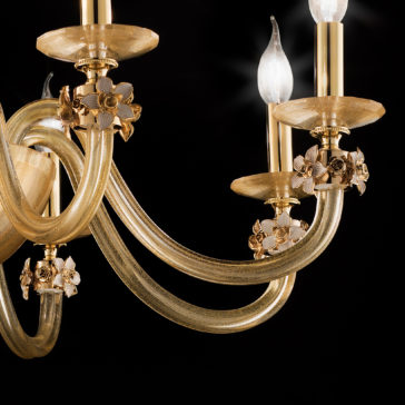8 Arm Hand Blown Glass Chandelier With Flowers A close-up of the refined 8 Arm Hand Blown Glass Chandelier With Flowers, showcasing its brass-colored curved arms and beautiful floral accents. The chandelier features candle-shaped light bulbs and ornate gold flowers, all highlighted against a black background that accentuates its intricate design.