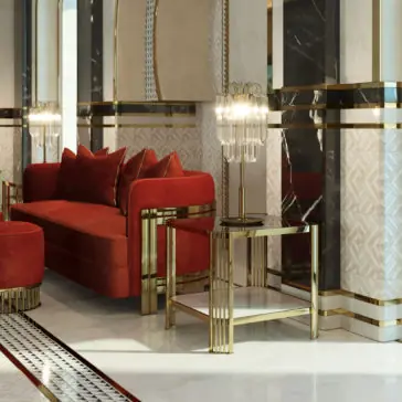 Art Deco Inspired Square Side Table A luxurious Art Deco-inspired living room featuring a plush red sofa with several matching cushions. An **Art Deco Inspired Square Side Table**, crafted from sleek gold and glass, stands beside the sofa adorned with an ornate glass lamp. The room is decorated with glossy marble surfaces and gold accents in geometric patterns.