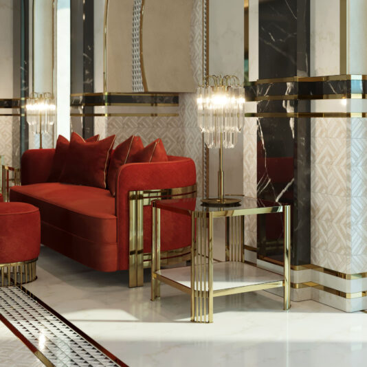 A luxurious Art Deco-inspired living room featuring a plush red sofa with several matching cushions. An **Art Deco Inspired Square Side Table**, crafted from sleek gold and glass, stands beside the sofa adorned with an ornate glass lamp. The room is decorated with glossy marble surfaces and gold accents in geometric patterns.