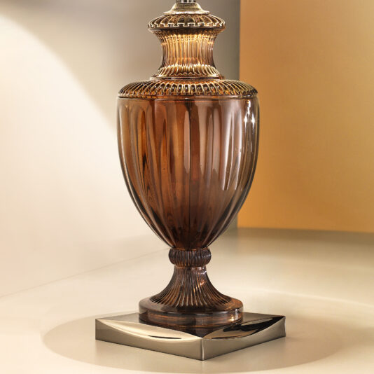 Introducing the Classic Style Brown Crystal Table Lamp: an elegant vintage-style table lamp featuring a translucent, bulbous, amber-colored glass base. The base is ornamentally ribbed and rests on a sleek, square metallic platform. This exquisite lamp casts a warm, inviting glow when lit.
