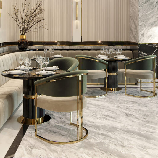 A luxurious, modern dining area features a mix of cream-colored, tufted banquette seating and plush, green velvet chairs with gold accents. The **Contemporary Lacquered Round Bistro Dining Set** and marble flooring complement the elegant ambiance, enhanced by minimalist wall decor and a vase of branches.
