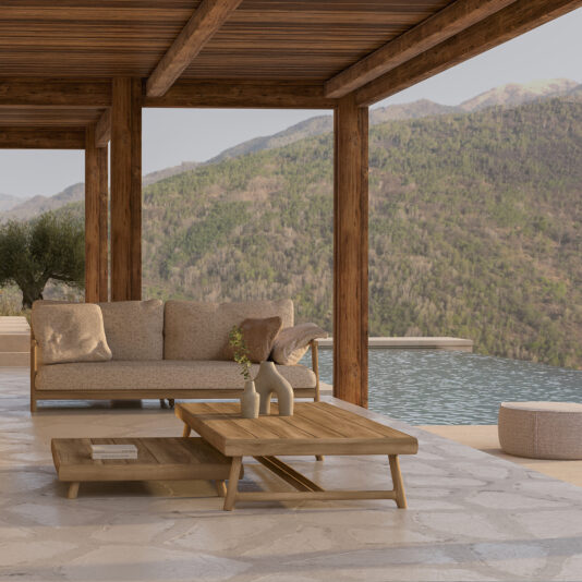 A serene outdoor patio features the Contemporary Outdoor Teak Sofa with cozy cushions, a wooden coffee table adorned with a vase, and a scenic view of lush green hills in the background. The patio is framed by wooden beams and overlooks a tranquil pool.