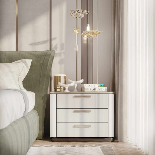 A modern bedroom features a sage green tufted headboard bed next to a white nightstand with three drawers. On the nightstand are a candle, a decorative antler, and a stack of books. Two Glass Pendant Lights Inspired By Nature hang above, and sheer curtains are drawn open.