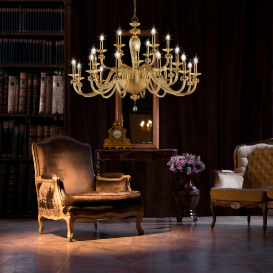 A dimly lit, elegant room features a Hand Blown Glass Chandelier With Flowers hanging from the ceiling. Below, an antique armchair and a tufted sofa flank a vase of purple flowers on a dark wooden floor. A large mirror reflects the chandelier above a vintage clock.