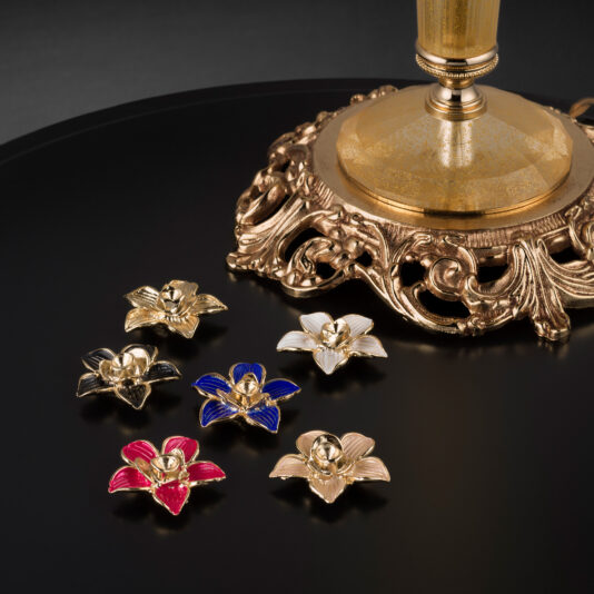 Hand Blown Glass Floor Lamp With Flowers A close-up of the Hand Blown Glass Floor Lamp With Flowers is displayed on a black surface. The ornate base features five hand-blown, flower-shaped glass candle holders in various colors: gold, red, blue, white, and purple. The photo captures the intricate details in a low-light setting.