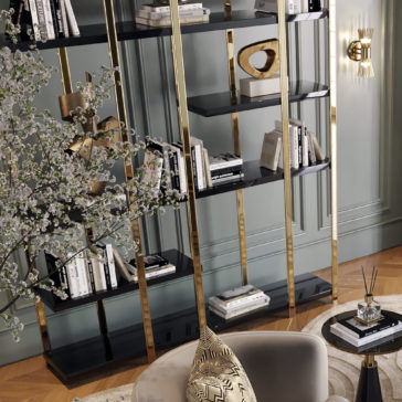 Large Modern Open Bookcase A stylish living room features the Large Modern Open Bookcase filled with books and decorative items, including a heart-shaped sculpture. A circular side table with abstract patterns, a plush gray chair, and a decorative tree branch add to the elegant decor.