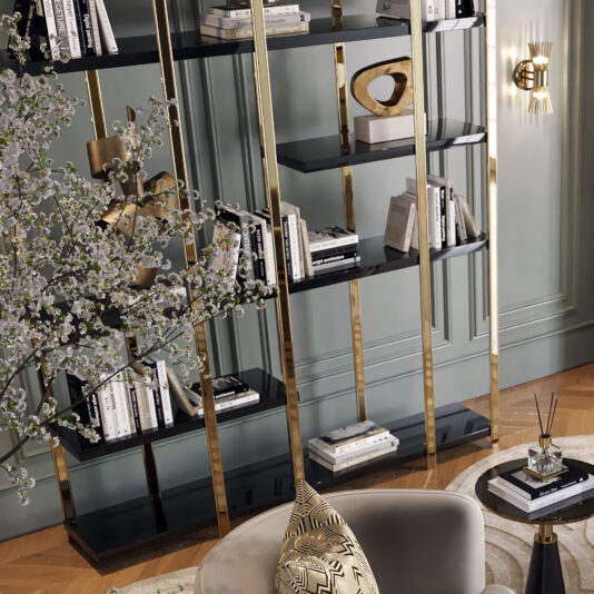 Large Modern Open Bookcase A stylish living room features the Large Modern Open Bookcase filled with books and decorative items, including a heart-shaped sculpture. A circular side table with abstract patterns, a plush gray chair, and a decorative tree branch add to the elegant decor.