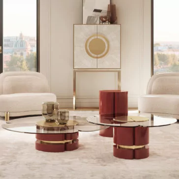 Modern Lacquered Coffee Table Set A contemporary living room showcasing a Modern Lacquered Coffee Table Set with red and gold bases, accompanied by beige upholstered chairs and a decorative console adorned with geometric artwork. Large windows allow natural light to flood the space while offering a stunning view of the cityscape in the background.