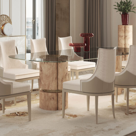 A modern dining room showcases the Modern Veneered Rectangular Glass Dining Table, which boasts a beige, abstract-patterned base and is paired with eight beige upholstered chairs. Contemporary red vase decor is displayed on a small pedestal. Large windows allow natural light to flood in, while beige curtains and a patterned rug add to the elegant ambiance.