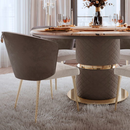 The dining room is beautifully adorned with a round table that boasts a quilted base and an elegant marble top. Surrounding the table are Two-Tone Contemporary Dining Chairs, distinguished by their sleek gold legs. The table is set with exquisite glassware and plates, while a vase filled with vibrant flowers serves as the centerpiece. A plush rug adds comfort to the space, which is bathed in natural light from large windows.