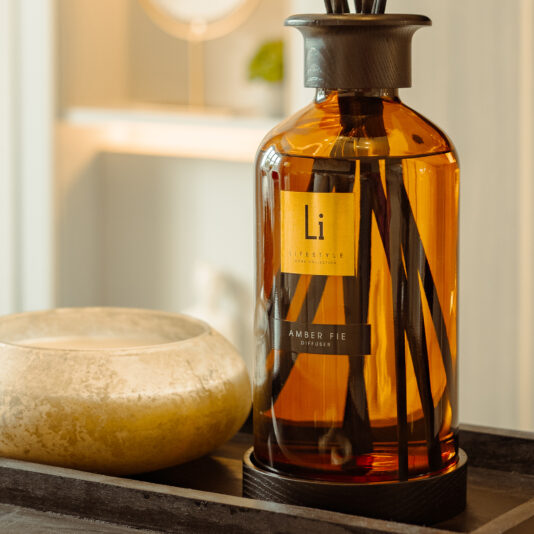 A close-up of an Extra Large Luxury Amber Fie Room Diffuser bottle with wooden reeds, bearing the 
