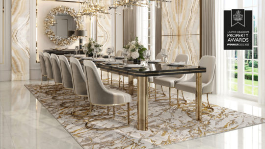 An elegantly decorated dining room featuring a long black and gold dining table with 12 white upholstered chairs. The room has marble walls and floor, a large decorative mirror, and chandeliers. On the wall, a plaque reads "United Kingdom Property Awards Winner 2022-2023.