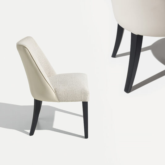 The High End Leather Backed Dining Chair, featuring a contemporary design with an off-white cushioned seat and backrest, is elegantly supported by four sleek black legs. It is displayed against a plain white background. The photo also provides a close-up view of the chair's legs and lower fabric on the right side.