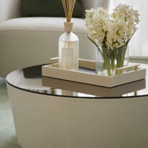 luxury round coffee table made in leather and glass top. with reed diffuser for home fragrance, flowers and decorative tray on top