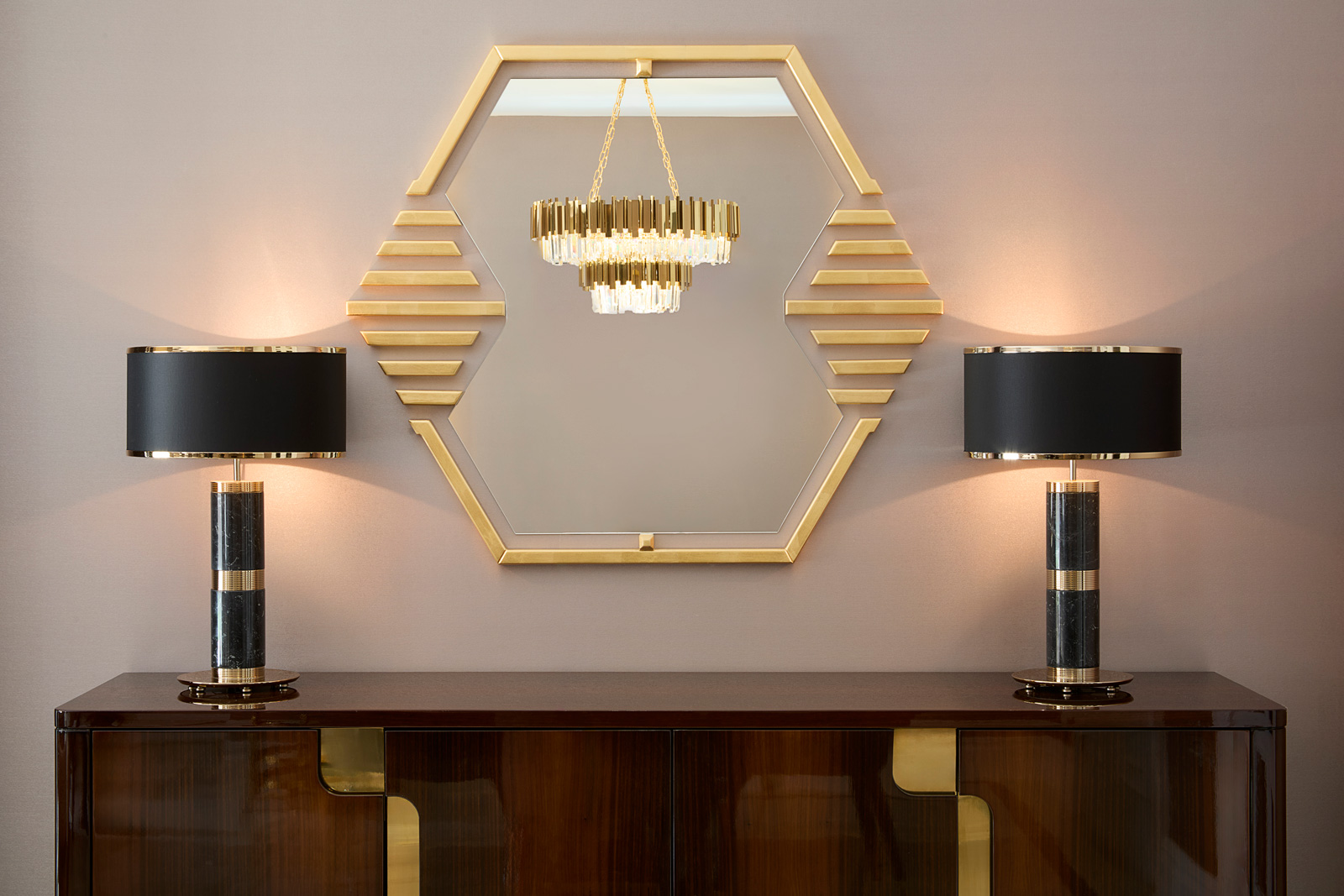 A modern interior at the design stage features a wooden console table with two black and gold lamps. A hexagonal mirror with gold accents hangs above, reflecting a gold and crystal chandelier, all set against a neutral beige wall.