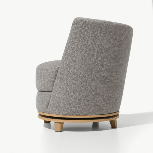 A gray upholstered chair with a rounded back and seat cushion, set on a swivel wooden base with short legs. The Curved Occasional Chair With Swivel Base is photographed from a rear and side angle against a plain white background.