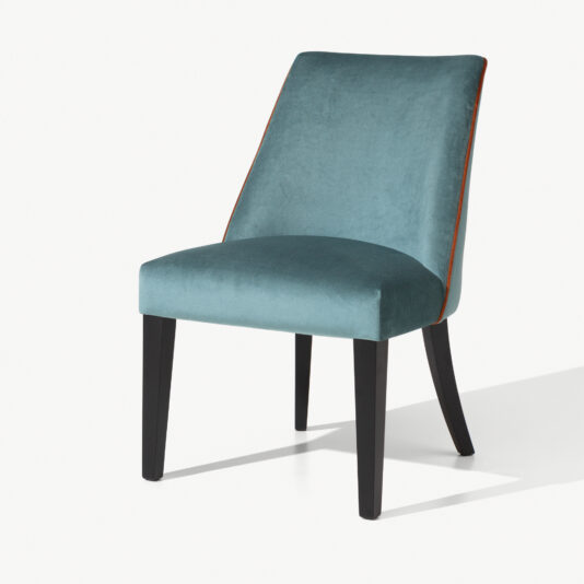 The High End Velvet Dining Chair With Piping features a luxurious turquoise upholstered seat and backrest, complemented by sleek black wooden legs. Its slightly angled backrest with piping detail exemplifies elegance and minimalist design, especially when highlighted against the white background.