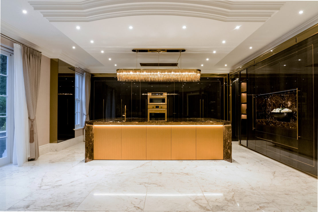 Wide angle view o Stunning art deco influenced luxury kitchen designed by Juliettes Interiors with statement modern chandelier, rich marble topped centre island with under bench lighting