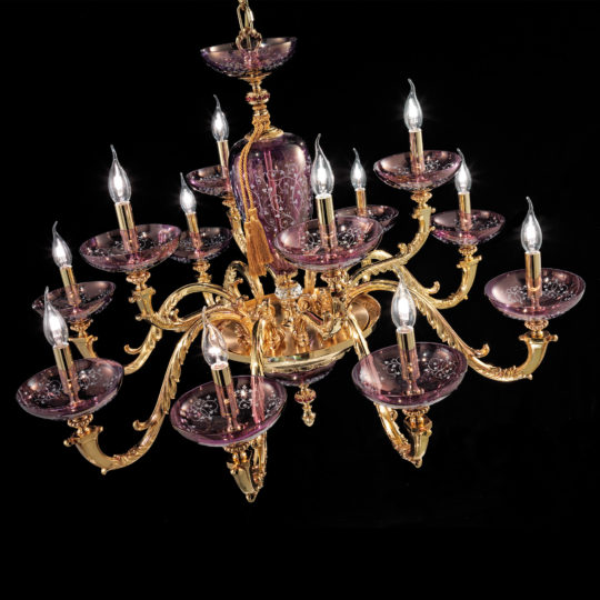 The Hand Blown Amethyst Glass Chandelier is a luxurious light fixture with gold detailing, boasting 15 ornate arms that each hold a candle-shaped light bulb. The bulbs are elegantly set on translucent hand-blown amethyst glass plates, creating a regal and sophisticated appearance against a black background.