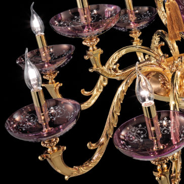 Hand Blown Amethyst Glass Chandelier A close-up of the Hand Blown Amethyst Glass Chandelier adorned with multiple candle-shaped light bulbs. The fixture showcases intricate golden metalwork and features elegant, hand-blown amethyst glass bowls with delicate white floral patterns, all set against a dark background.